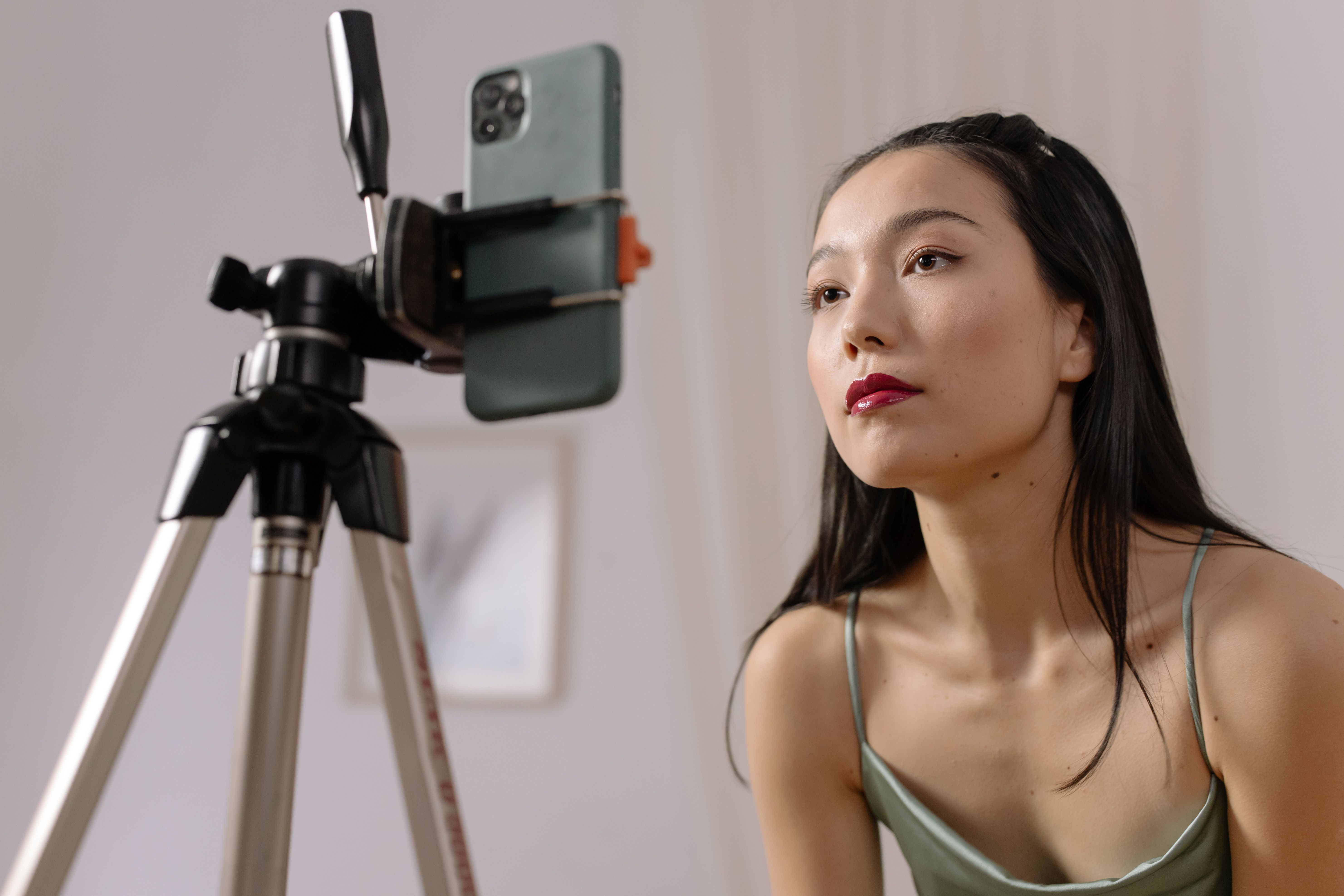 Woman recording a vlog with a smartphone on a tripod, representing self-promotion and attention-seeking