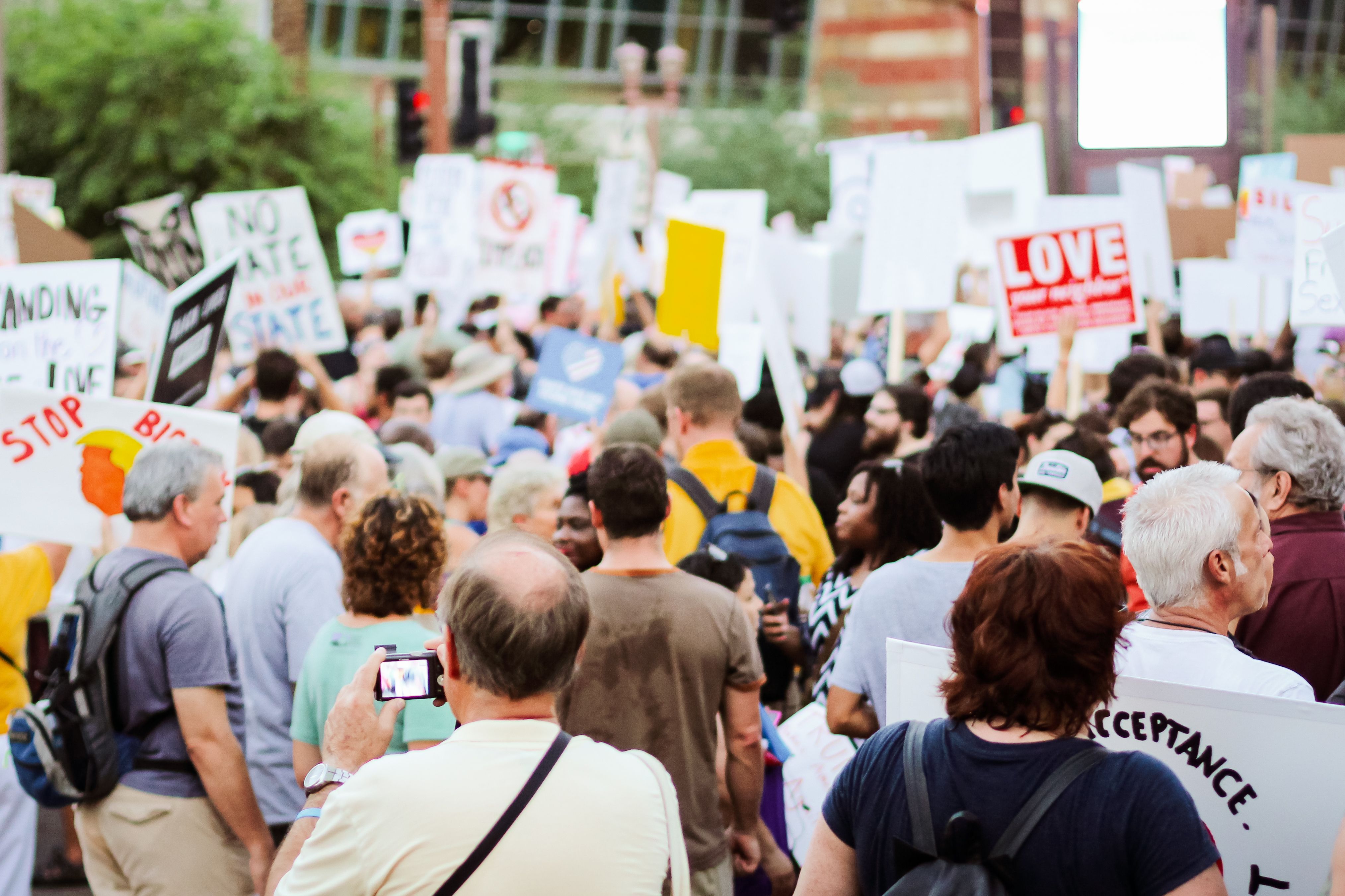 Back view of a crowd with banners and placards at a protest, representing devoted supporters rallying for a cause