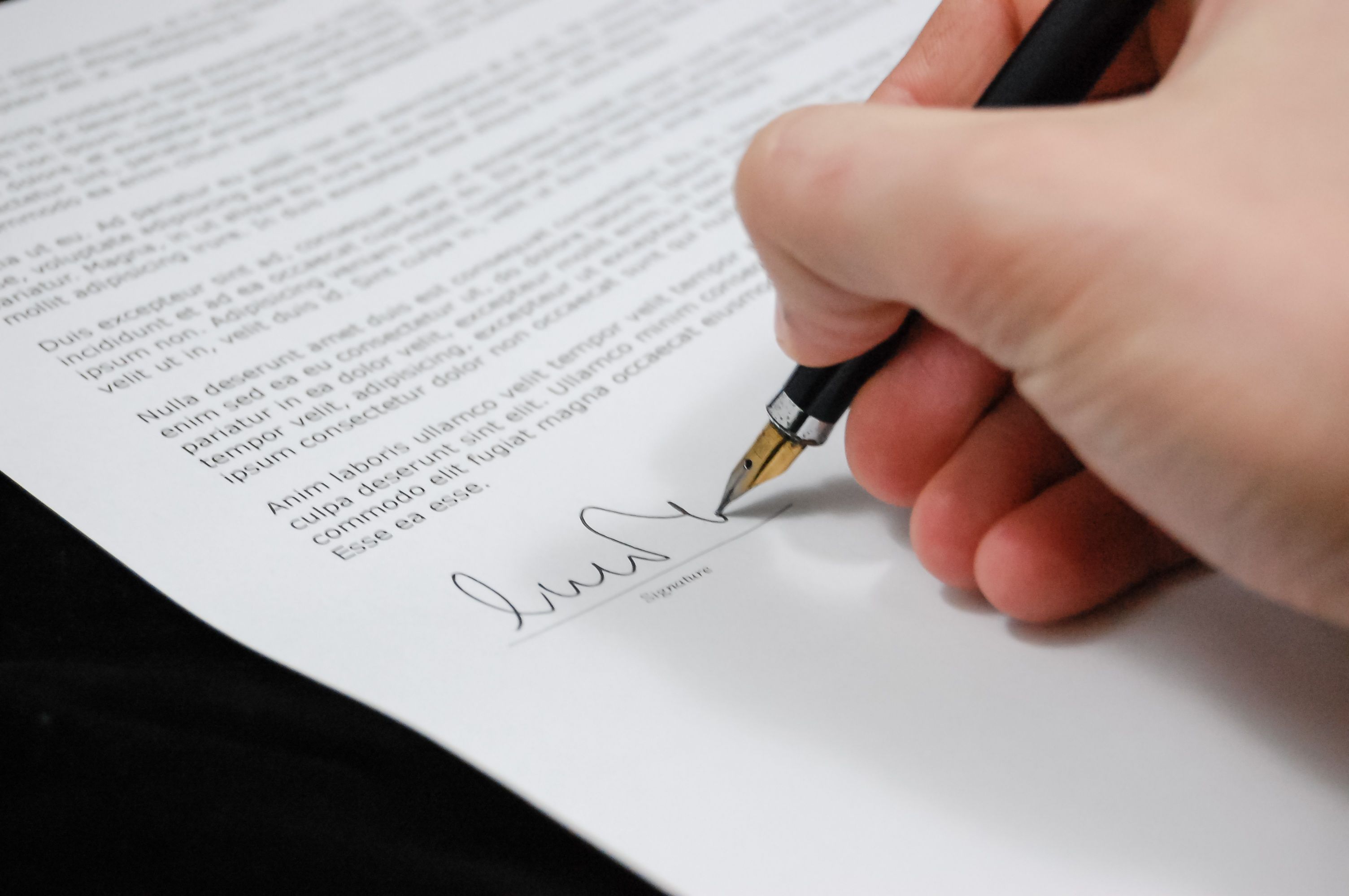 Close-up of a hand signing a legal funding agreement with a fountain pen