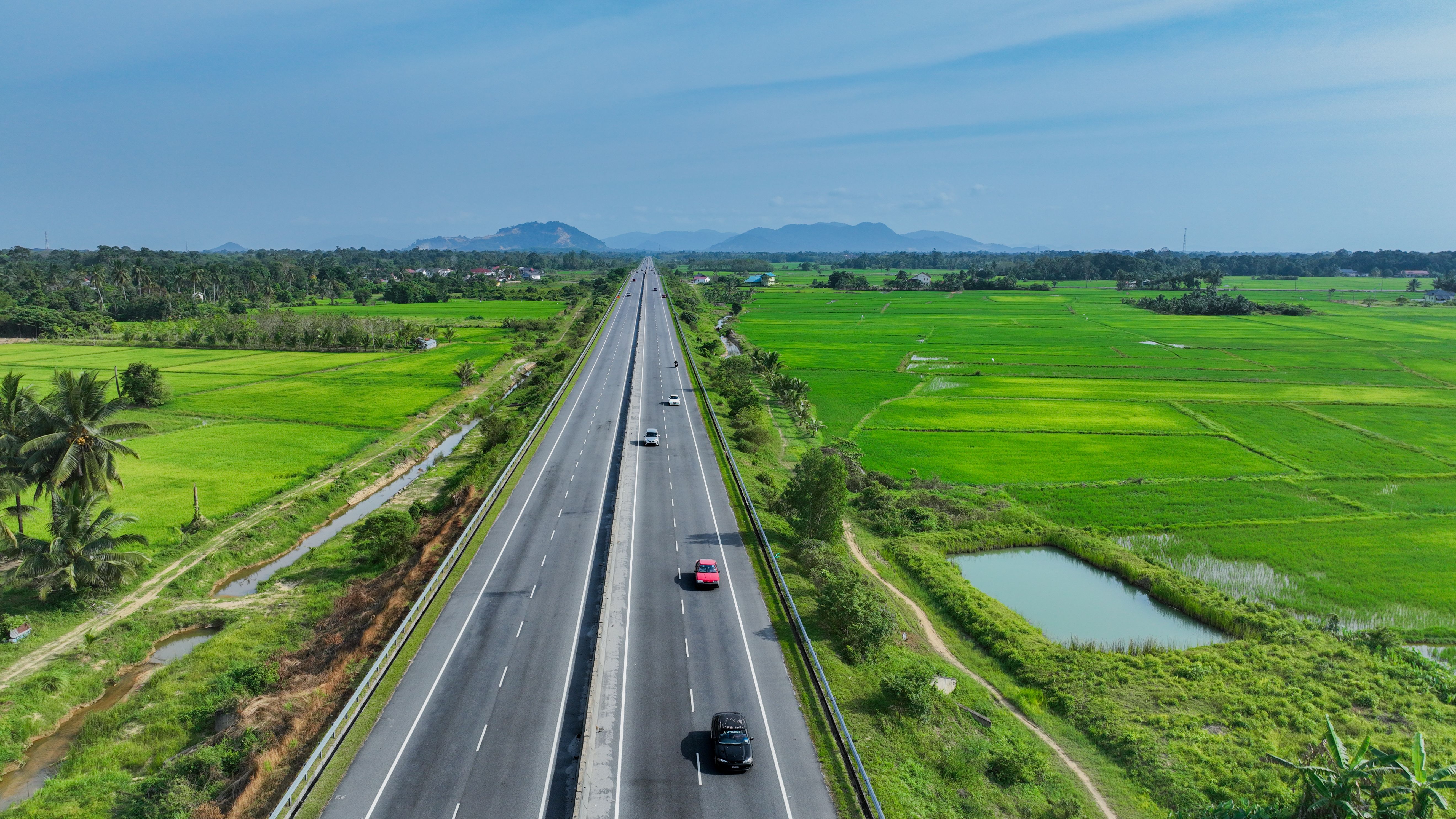 Highway crossing green paddy fields in Kota Bharu, Malaysia, illustrating transport links and regional growth